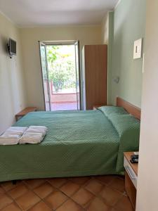 Schlafzimmer mit einem Bett mit grüner Tagesdecke in der Unterkunft Ravè in Praia a Mare
