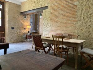 uma mesa e cadeiras num quarto com uma parede de tijolos em la maison de Manon em Mirande