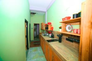 a large kitchen with green walls and wooden cabinets at Ammu villa in Point Pedro