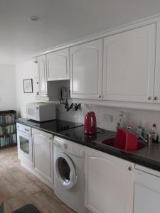a kitchen with white cabinets and a washing machine at Chauffeur's, Snape in Saxmundham