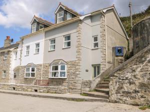 a white house on a street next to a wall at Sea Star in Porthleven