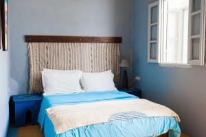Schlafzimmer mit einem Bett mit blauen Wänden und einem Fenster in der Unterkunft Riad Dar Lina in Rabat
