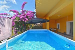 - une piscine avec des fleurs violettes et un parasol dans l'établissement Apartment Miha, à Loborika