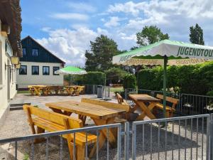 a group of picnic tables with an umbrella at Jugendtours-Feriendorf Ummanz in Ummanz
