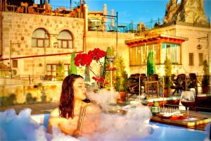 a woman in a bath tub with a glass of wine at Historical Goreme House in Goreme