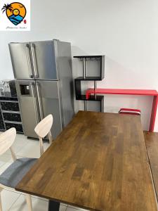 ZZZ HOMESTAY SKUDAI في سكوداي: مطبخ مع طاولة خشبية وثلاجة