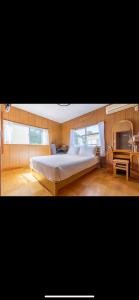 a bedroom with a large bed and a desk at Bonel Guest House in Tomisato