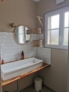 La salle de bains est pourvue d'un lavabo blanc et d'un miroir. dans l'établissement Les gîtes de Blandine, à Peumérit