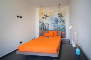 B&B Coccaluto 39 في Castrignano deʼ Greci: غرفة نوم بسرير برتقالي مع لوحة على الحائط