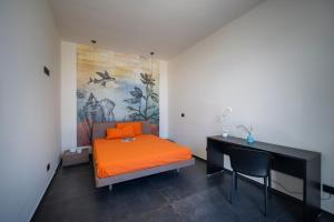 B&B Coccaluto 39 في Castrignano deʼ Greci: غرفة نوم مع سرير برتقالي ومكتب