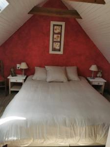 - une chambre avec un lit blanc et un mur rouge dans l'établissement Les gîtes de Blandine, à Peumérit