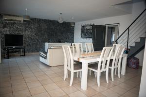 una sala da pranzo con tavolo e sedie bianchi di La case à Nath - Piscine chauffée et jacuzzi a Saint-Pierre