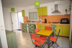 a kitchen with green cabinets and a table and chairs at La case à Nath - Piscine chauffée et jacuzzi in Saint-Pierre