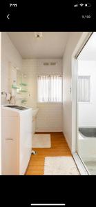 a white bathroom with a sink and a tub at Bonel Guest House in Tomisato