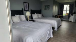um quarto de hotel com duas camas com lençóis brancos em Hotel-Motel Le Panorama em Perce