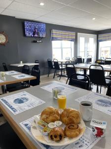 a table with a plate of pastries and orange juice at Hotel-Motel Le Panorama in Perce