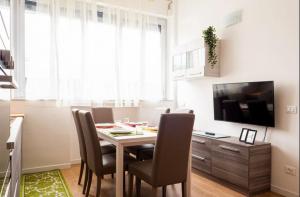 a dining room with a table and chairs and a television at Vera Project Apartment in Milan