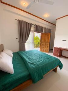 a bedroom with a green bed and a window at The Reef Resort in Nilaveli