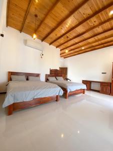 two beds in a room with white walls and wooden ceilings at The Reef Resort in Nilaveli