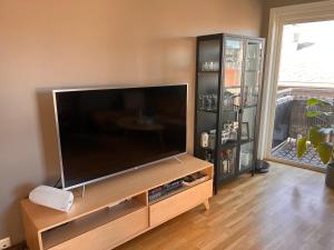 a large flat screen tv sitting on a wooden entertainment center at Solsiden, 2 soverom med parkering in Trondheim