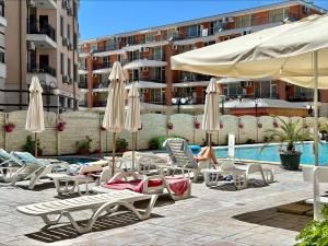 a group of chairs and umbrellas next to a pool at Blue Marine - Menada Apartments in Sunny Beach