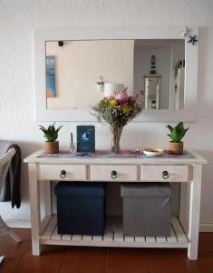 a dressing table with a mirror and flowers on it at Macs Cove, Marina Martinique in Jeffreys Bay