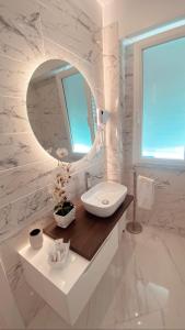 Baño blanco con lavabo y espejo en Meligrana Central Rooms en Tropea