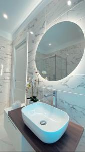 Baño blanco con lavabo y espejo en Meligrana Central Rooms en Tropea