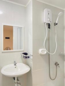 a white bathroom with a shower and a sink at Aimee Exquisite Spaces in Iloilo City