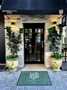 a building with two potted plants in front of a door at Levinski Market Hotel in Tel Aviv