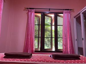 a bedroom with a window with pink curtains at Happy Resort in Khanom
