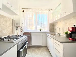 Una cocina con gabinetes blancos y un fregadero y una ventana. en Single room Perfect for couples or singles, en Roşu
