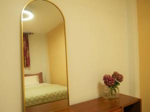 a mirror in a bedroom with a bed and a vase of flowers at Green Cozy Nest in Paleo Tsifliki