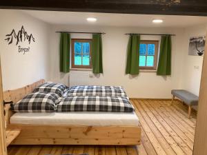 Ce lit se trouve dans un dortoir doté de rideaux verts. dans l'établissement Bandltroga, à Murau