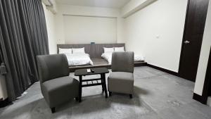 a bedroom with a bed and two chairs and a table at Doremi B&B in Baisha