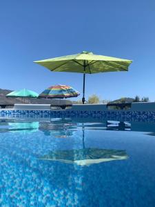 a swimming pool with an umbrella and some chairs at Cortijo La Vista in Órgiva