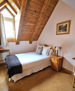 Un dormitorio con una gran cama blanca y una ventana en Hotel Anglada, en Vielha