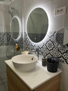 a bathroom with a sink and two mirrors at Superbe appartement moderne en rez-de-chaussée in Ozoir-la-Ferrière