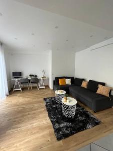 a living room with a black couch and a rug at Superbe appartement moderne en rez-de-chaussée in Ozoir-la-Ferrière