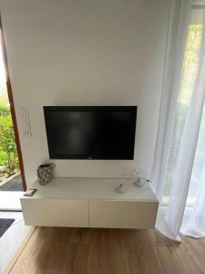 a white living room with a flat screen tv at Superbe appartement moderne en rez-de-chaussée in Ozoir-la-Ferrière