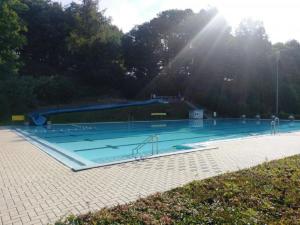 a large swimming pool with the sun shining at Ferienhaus Laange in Frankenau