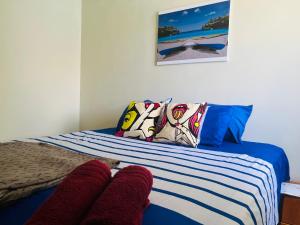 a bed with blue and white striped sheets and pillows at Bon Bini Kokolishi in Willemstad