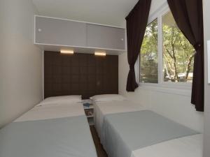 two beds in a room with a window at Detached chalet with AC, in a natural park on the coast in Baia Domizia