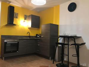 a kitchen with a sink and a counter with stools at *Le Yellow -Appartement T2, hypercentre* in Limoges