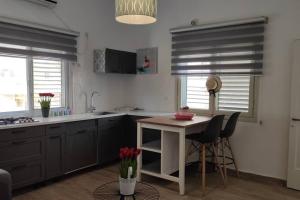 a kitchen with black cabinets and a table with red flowers at Stylish Quiet and Central in Rechovot