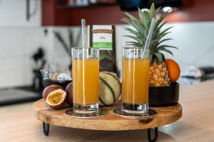 two glasses of orange juice on a wooden tray at Le Prestige* * * * - Minibar Gratuit - Parking in Saint-Pierre