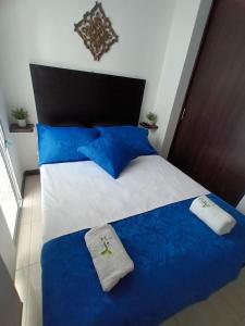 1 dormitorio con cama con sábanas azules y blancas y almohadas azules en Colibrí Cafeterito, en Montenegro