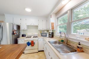 een keuken met witte kasten, een wastafel en een koelkast bij Sea Gem Hideaway in South Dennis