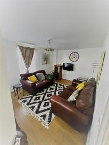 una sala de estar con 2 sofás de cuero marrón y una alfombra en Beautiful 4 Bedroom Treasure home en Hemel Hempstead