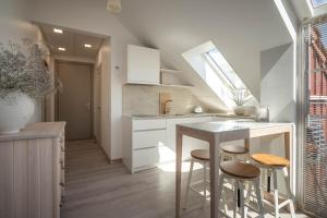 a kitchen with a table and two stools at Nauji apartamentai! Pamario 14 in Nida